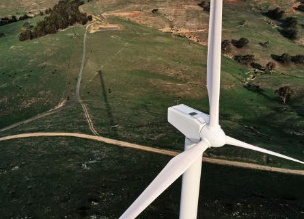 Arial shot of a wind turbine on a backdrop of green fields