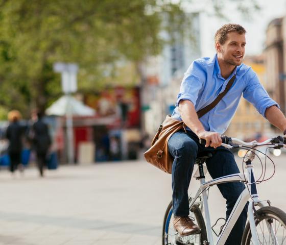 Smiling man in blue skirt bycycling threw city