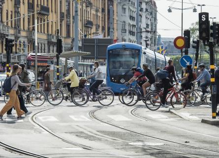 People cycling across the street, tram in the background