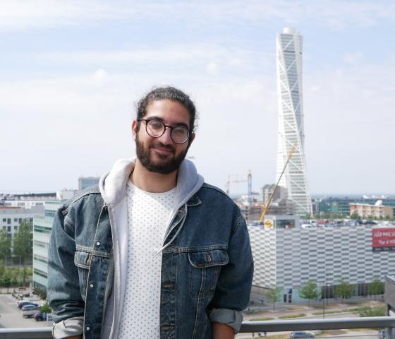 Nima standing in front of Turning Torso in Malmö with his hands in his pockets